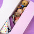 Assorted donuts and a colorful polka dot cone in a purple box.