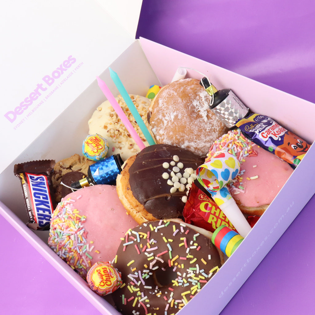 Assorted donuts and candy in a box with a purple background