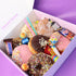 Assorted donuts and candy in a box with a purple background