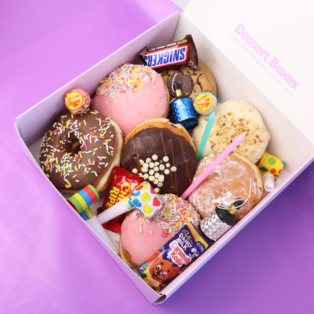 Assorted donuts and candies in a box on a purple background