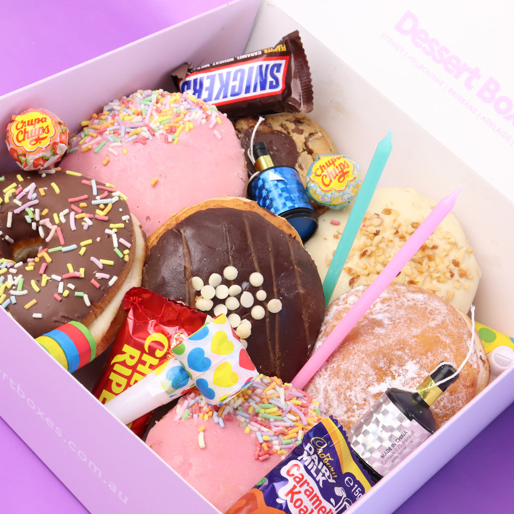 Assorted donuts and candies in a box with visible brand names.