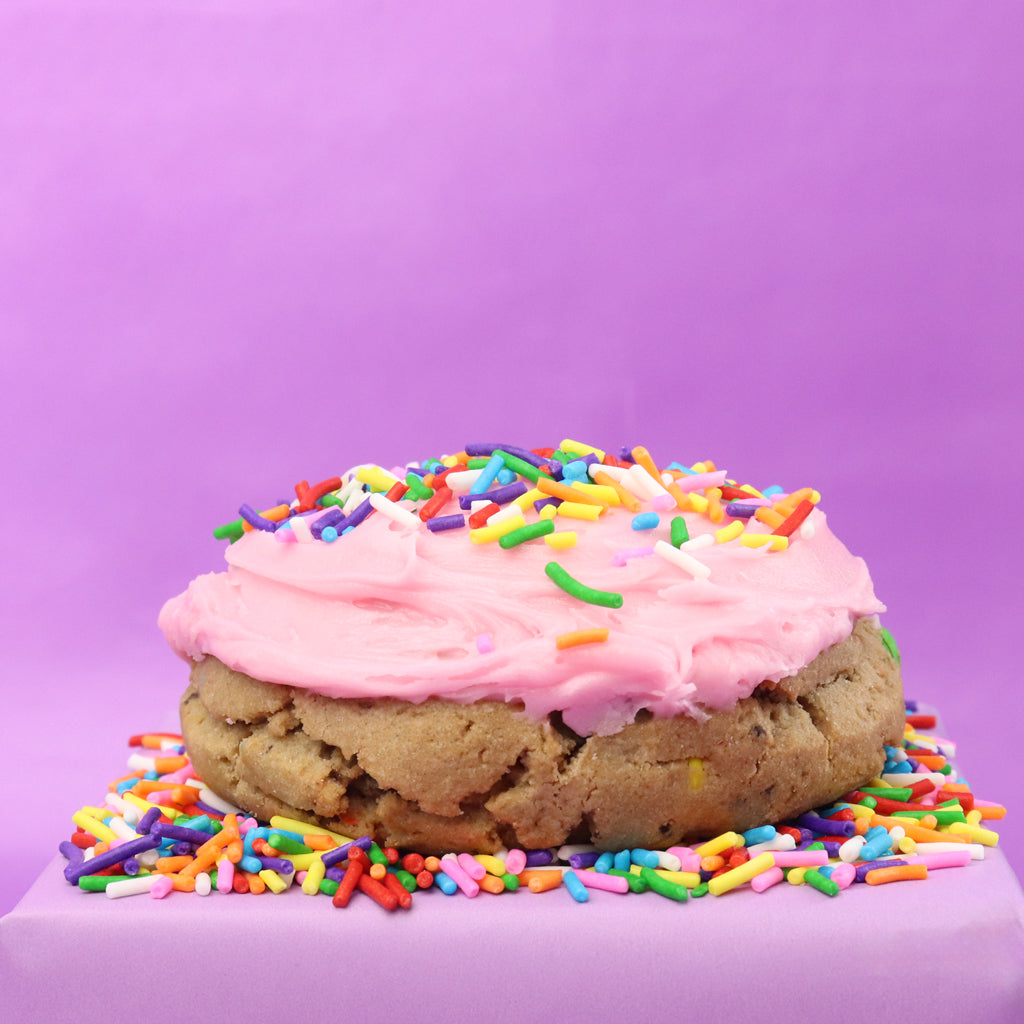 Cookie with pink frosting and colorful sprinkles