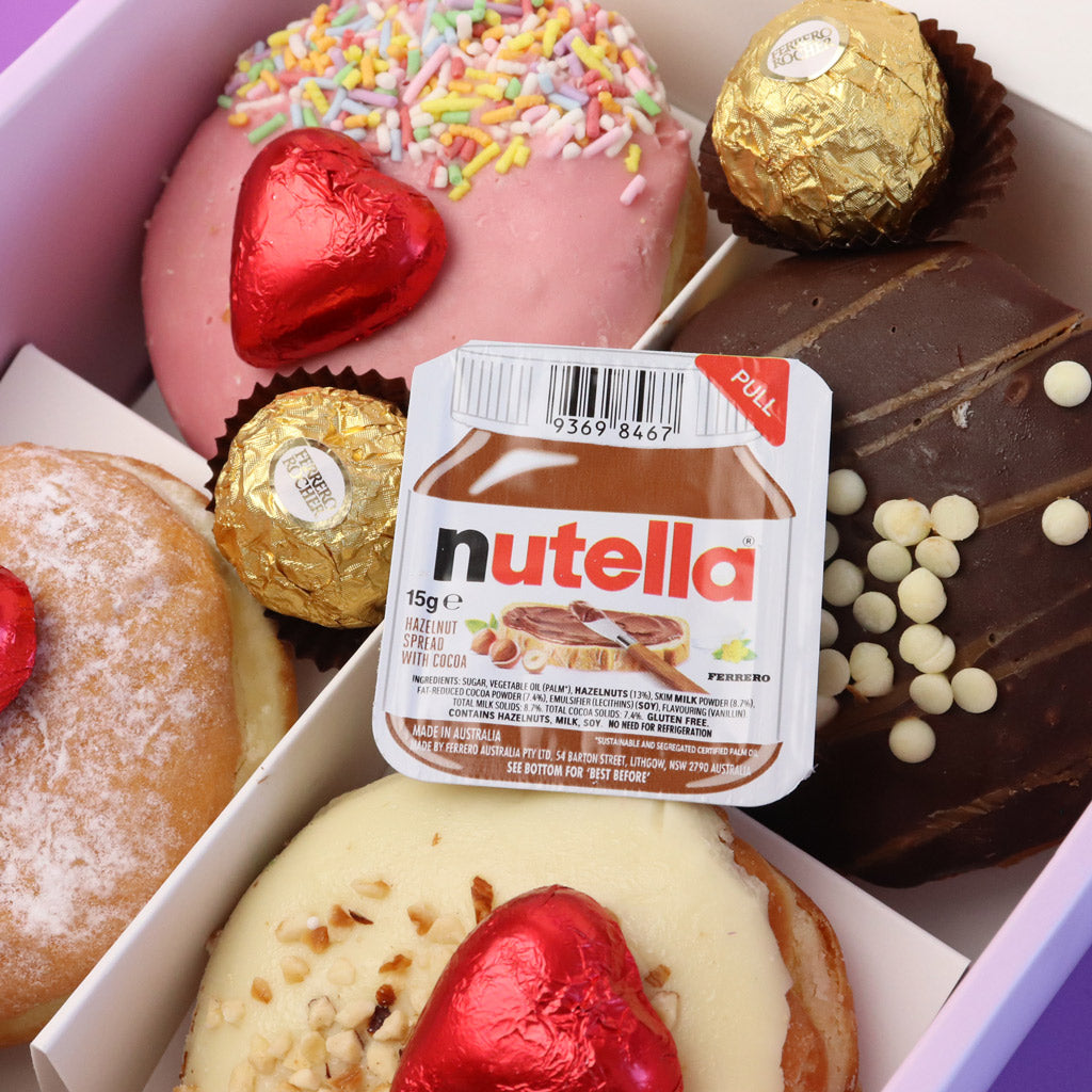 Box of assorted donuts with a Nutella spread container in the centre with Ferrero Rocher and Heart Chocolates.