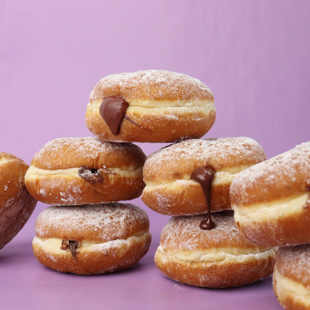 Stack of filled donuts with chocolate filling on a purple background