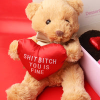 Teddy bear holding a red heart pillow with text, sitting on a red surface.