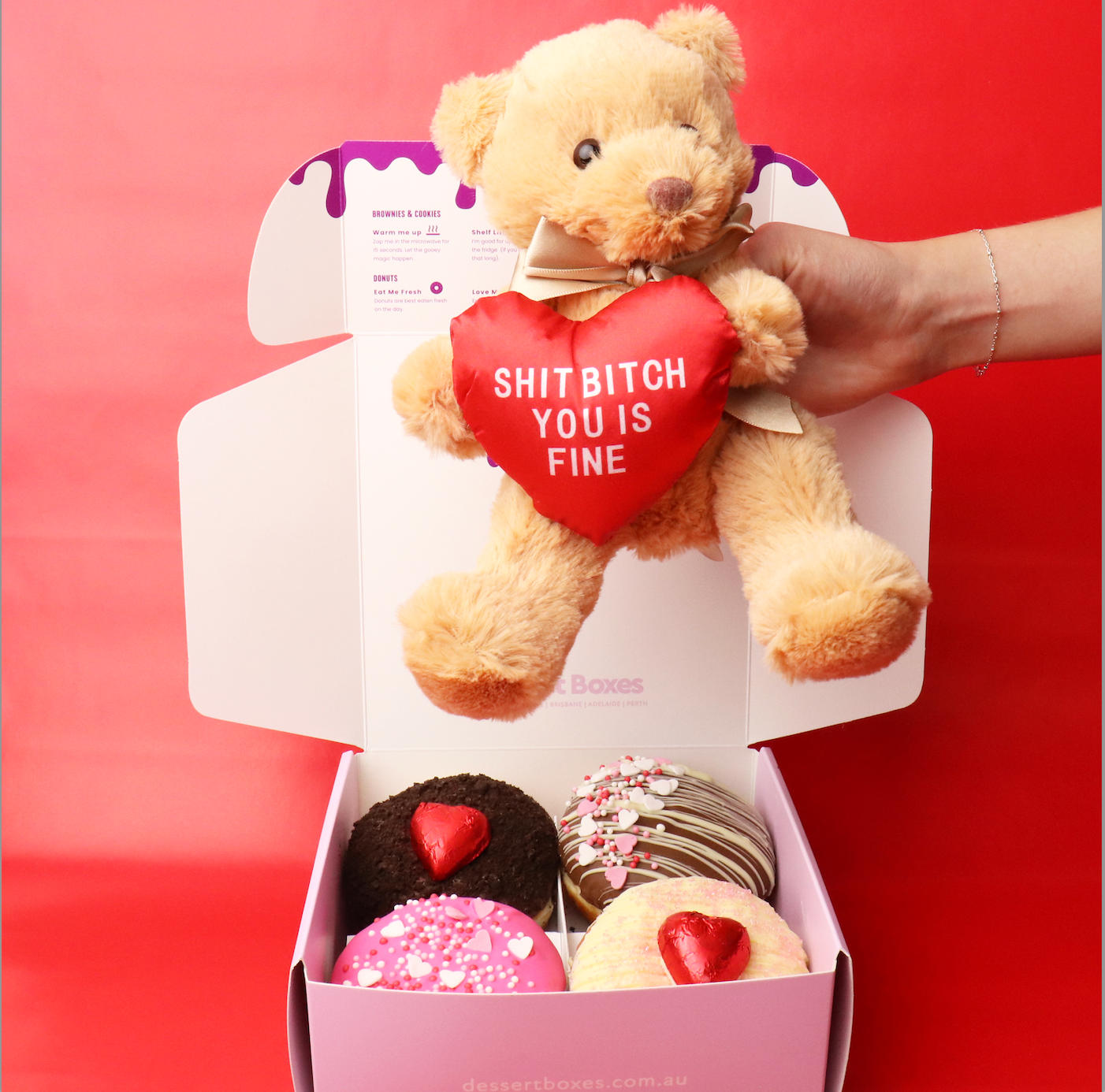 Teddy bear with a heart-shaped pillow and donuts in a box