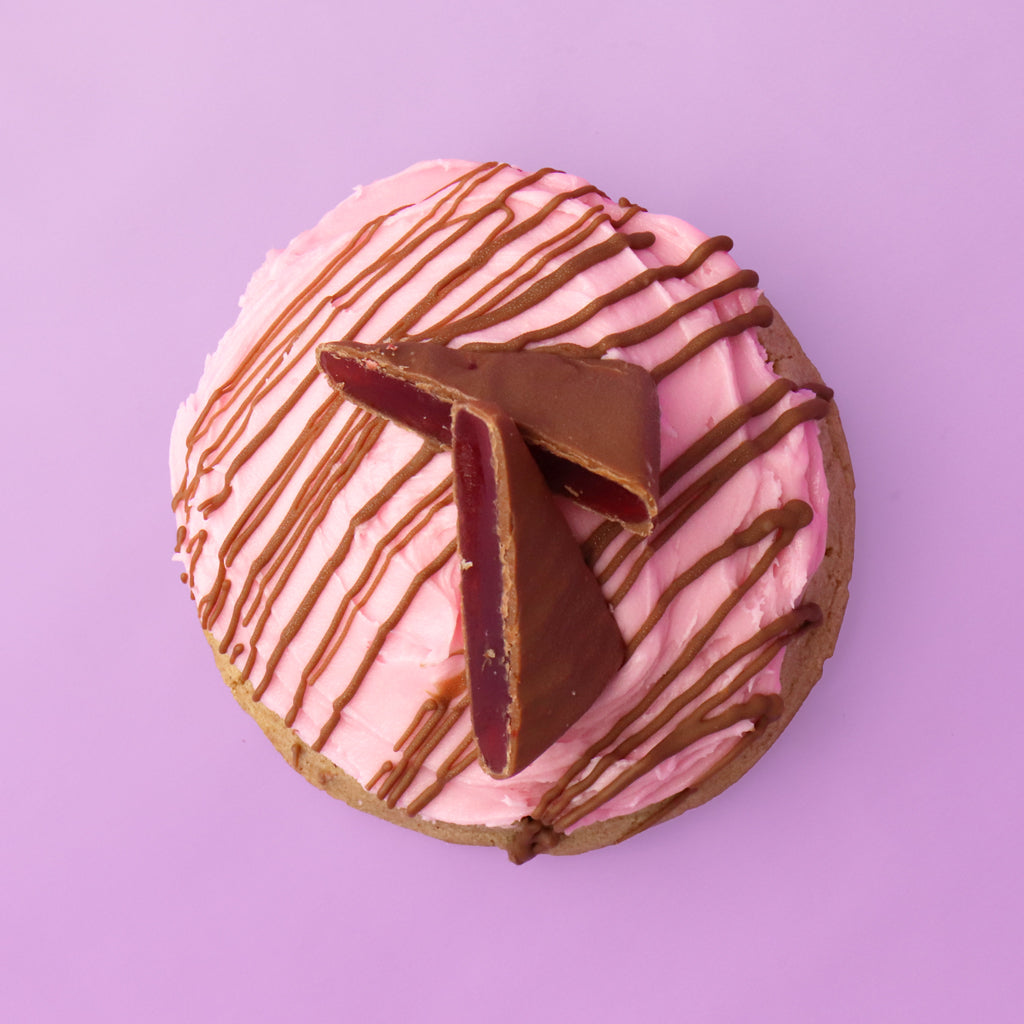 Donut with pink glaze and chocolate drizzle on a purple background