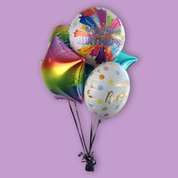 A bouquet of colorful balloons including two with 'Happy Birthday' text, tied together with a balloon weight.